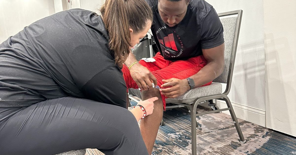 An athletic trainer is equipped with a recovery device for an experiment using KINEXON Sports data.