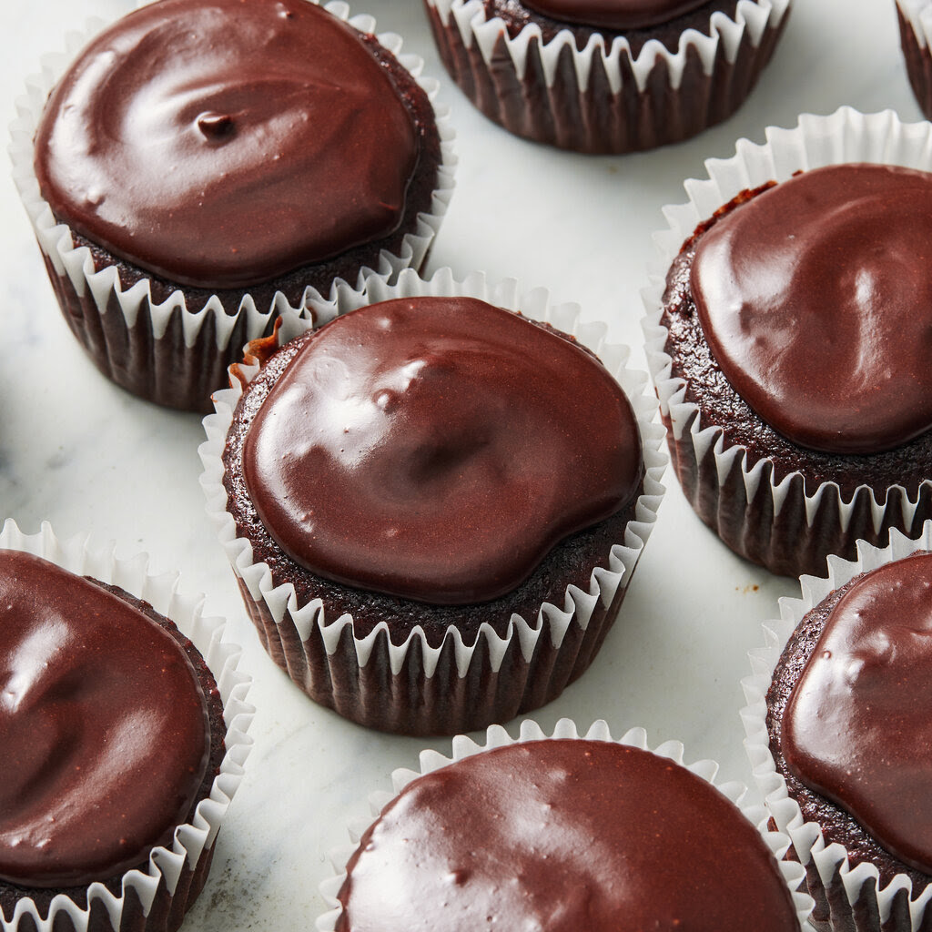 Several chocolate cupcakes on a white countertop.