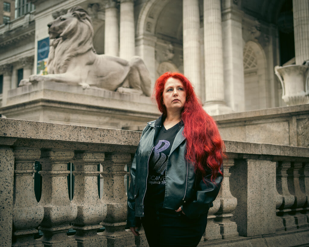 A woman with red hair next to one of the New York Public Library’s lions.