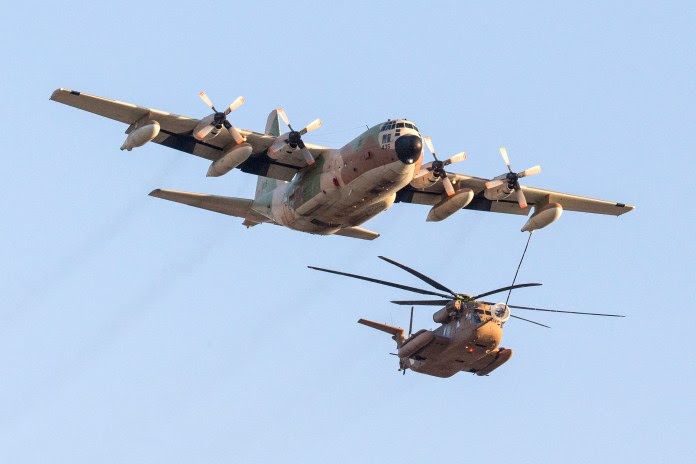 Un avion israélien C-130 Hercules ravitaille un hélicoptère Sikorsky CH-53K alors qu'ils participent à un spectacle aérien pour une cérémonie de remise de diplômes à la base de Hatzerim dans le désert du Néguev, près de la ville israélienne de Beersheva, le 31 décembre 2015. AFP PHOTO / JACK GUEZ (Photo de JACK GUEZ / AFP) (Photo de JACK GUEZ/AFP via Getty Images)