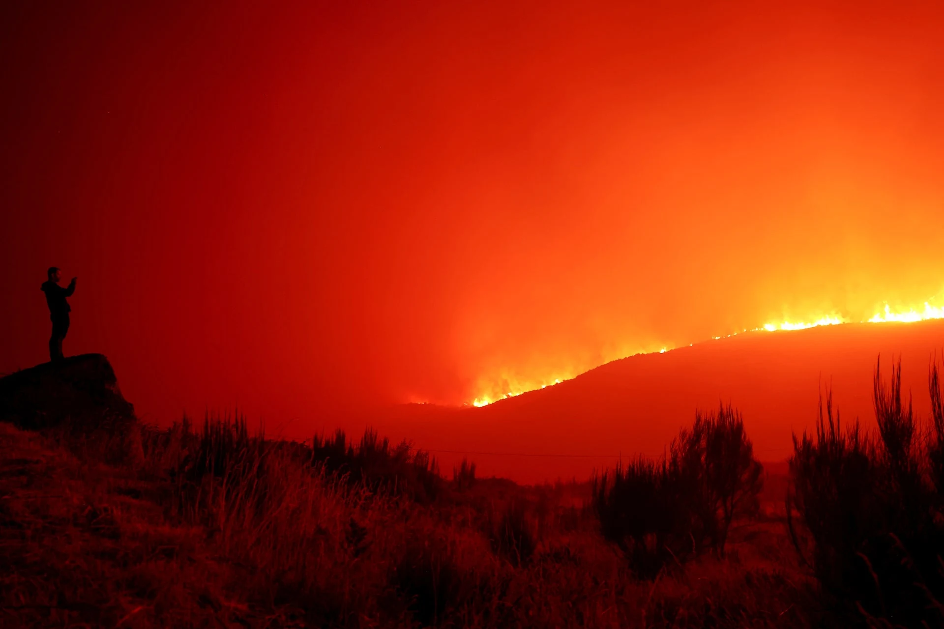 A man stands in the vicinity of wildfire, near Povoa de Montemuro, Portugal