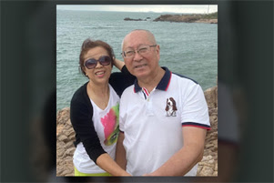 Elder Hao Ming is sitting with his wife at a shoreline.
