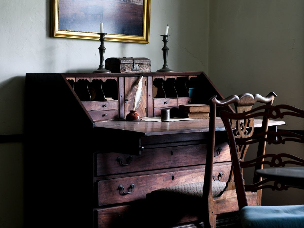 An elegant, old fashioned desk with a quill and ink container in an old house.