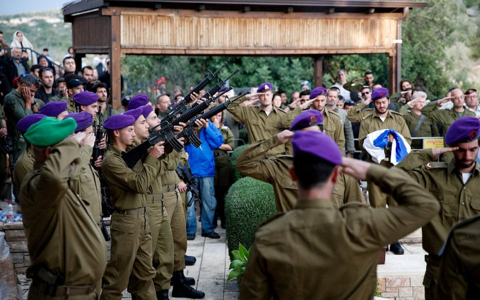 Soldiers hold weapons during the funeral of an Israeli military reservist