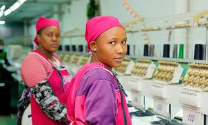 Trabajadoras de la confección junto a una línea de máquinas de coser en una fábrica de ropa de Lesotho.