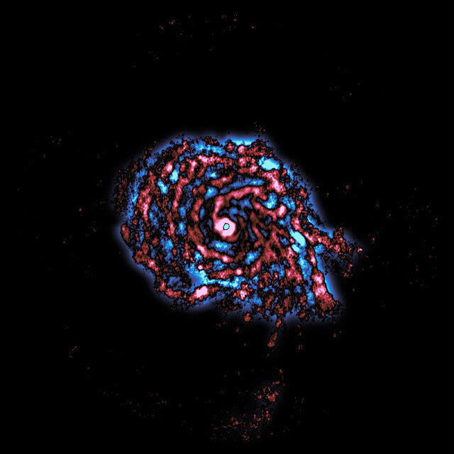 A computerized telescope image shows a swirling mass of blues and reds on a black background.