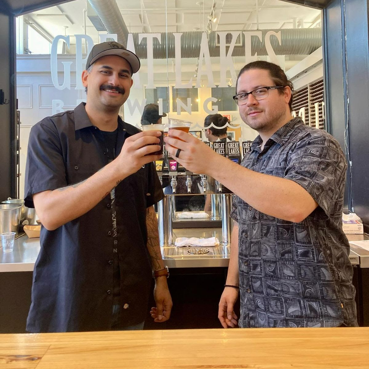 Two tour guides toasting with beer samples in the GLBC Beer Symposium tour center.