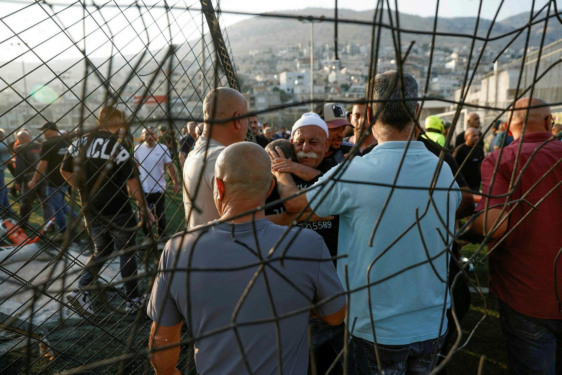 Local residents comfort each other as they gather at a site where a reported strike from Lebanon fell in Majdal Shams village in the Golan, on Saturday.