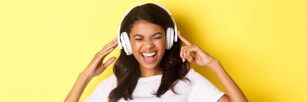 Smiling girl listening to audio on headphones.