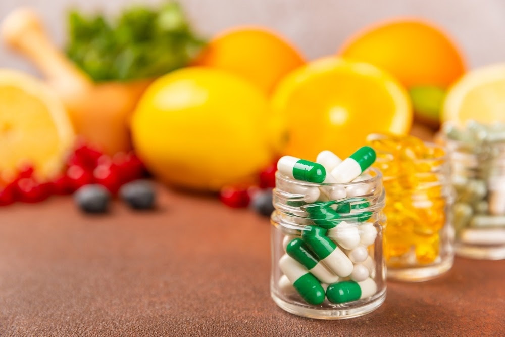 A variety of vitamin tablets in a jar on a textured background.