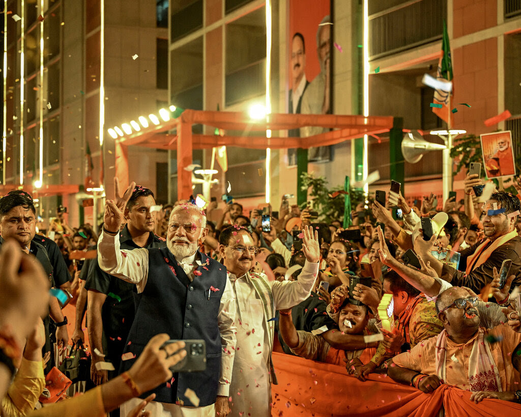 Narendra Modi walking and waving to throngs of supporters.