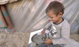 Un niño pequeño recoge los últimos granos de arroz de su cuenco. El hambre se dispara en Gaza y los alimentos del PMA autorizados a entrar son limitados