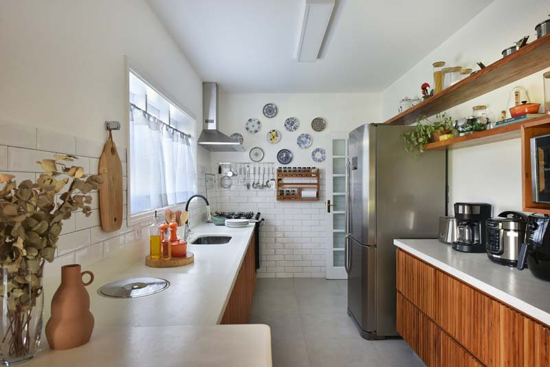 Muito bem explorada pela arquiteta Rosangela Pena, a cozinha tem um apelo afetivo e retrô com o revestimento subway tile e a coleção de pratos expostos na parede | Foto: Sidney Doll