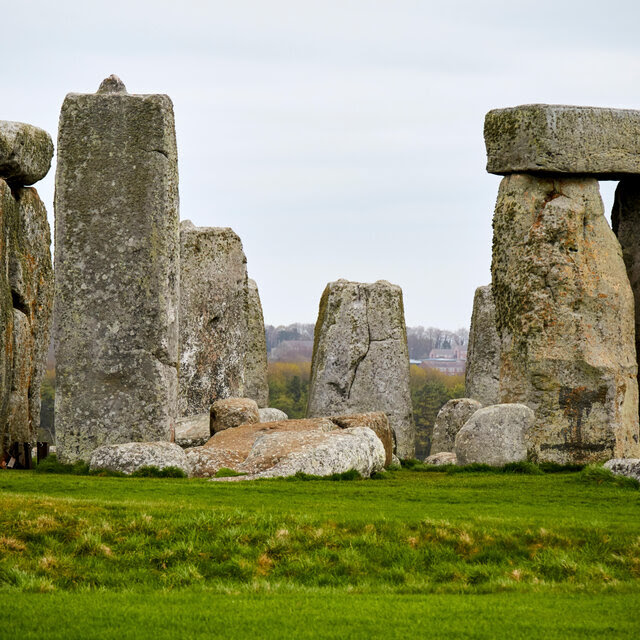 A view from some ways away looking at the inner ring of Stonehenge monoliths on an overcast day.