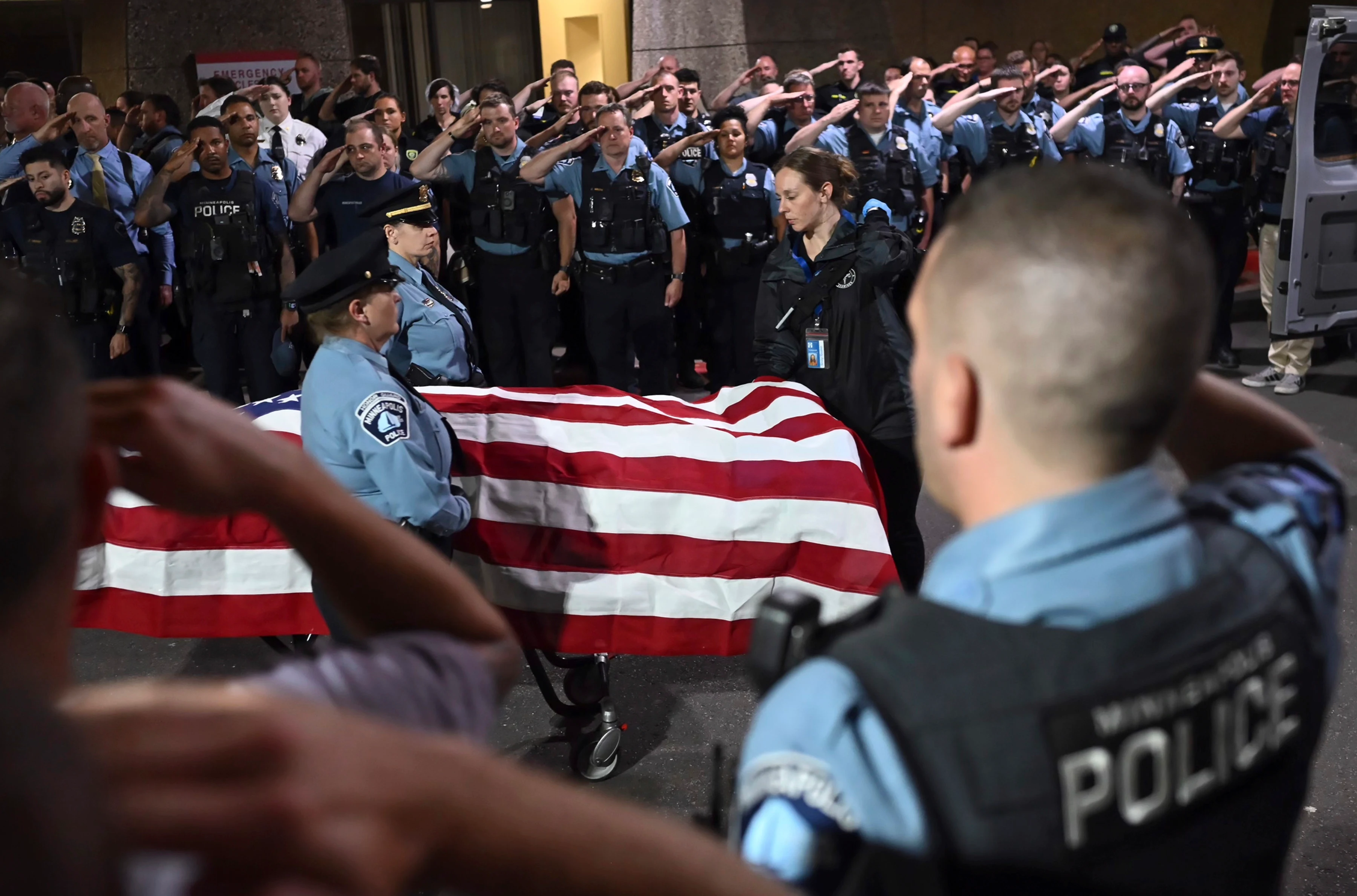 Law enforcement officers salute the flag-draped remains of fallen Minneapolis police Officer Jamal Mitchell as he is escorted to a waiting medical examiner's vehicle outside Hennepin County Medical Center in Minneapolis on Thursday. (Aaron Lavinsky/Star Tribune via AP)