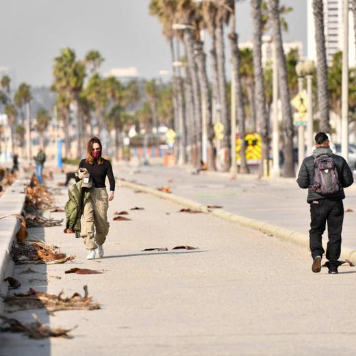 People wear masks because of hazardous air quality due to the wildfires as they walk by the beach in Santa Monica, California, on January 8, 2025. A ferocious wildfire in a Los Angeles suburb devoured buildings and sparked panicked evacuations January 7, as hurricane-force winds tore through the region. More than 200 acres (80 hectares) was burning in Pacific Palisades, a upscale spot with multi-million dollar homes in the Santa Monica Mountains. Across town, on the northern edge of Los Angeles, another fire broke out in Eaton Canyon, near Pasadena, quickly consuming 200 acres (81 hectares) later in the night, according to Angeles National Forest officials. (Photo by Chris DELMAS / AFP)