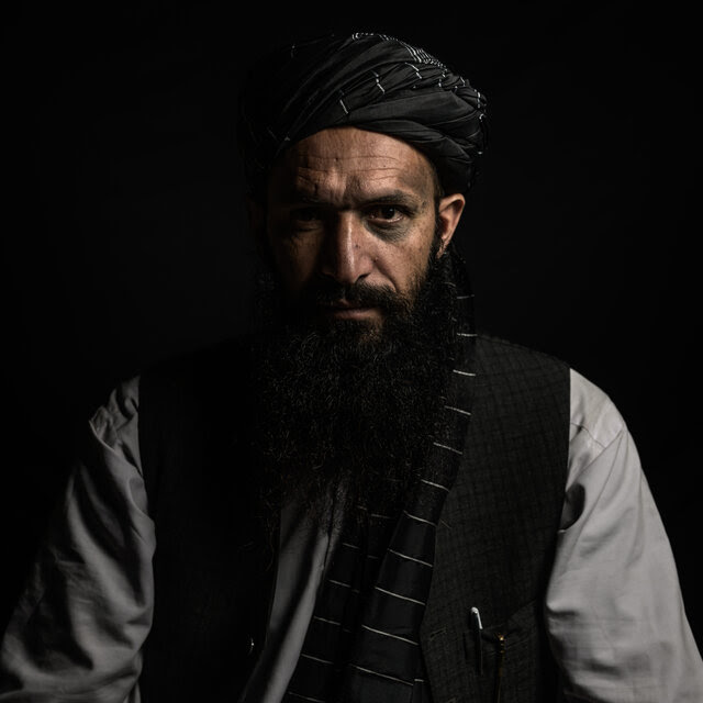 A portrait of a man facing the camera in gray and black attire.