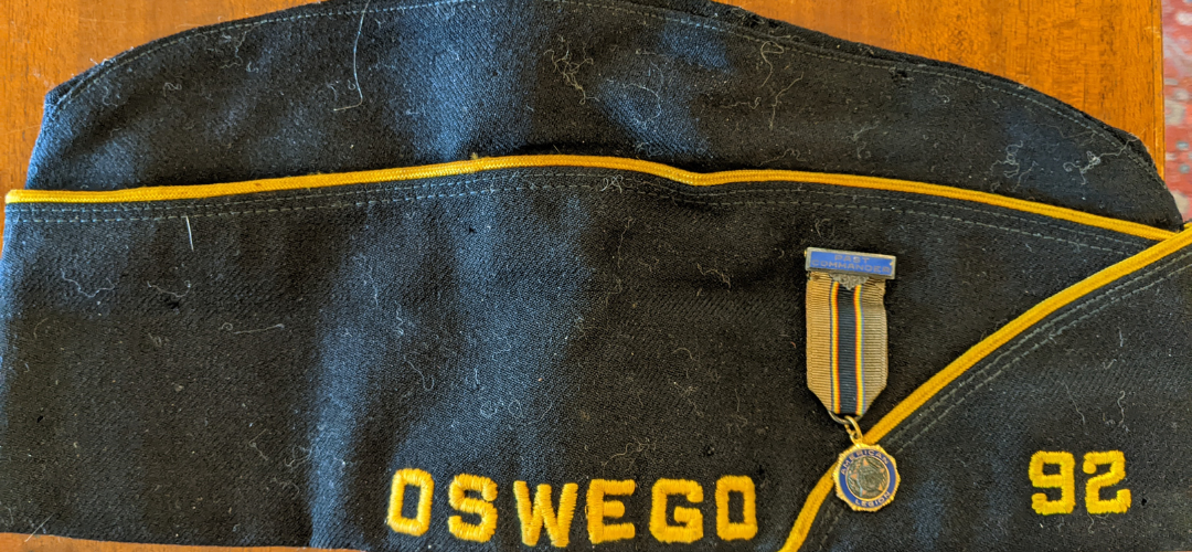 photograph of an american legion hat that is blue and gold with the words "oswego 92" on it