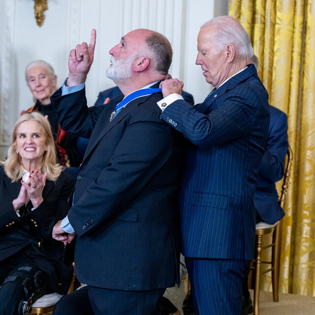 Chef and head of World Central Kitchen Jose Andres points to the sky as he receives a medal around his neck from President Joe Biden.