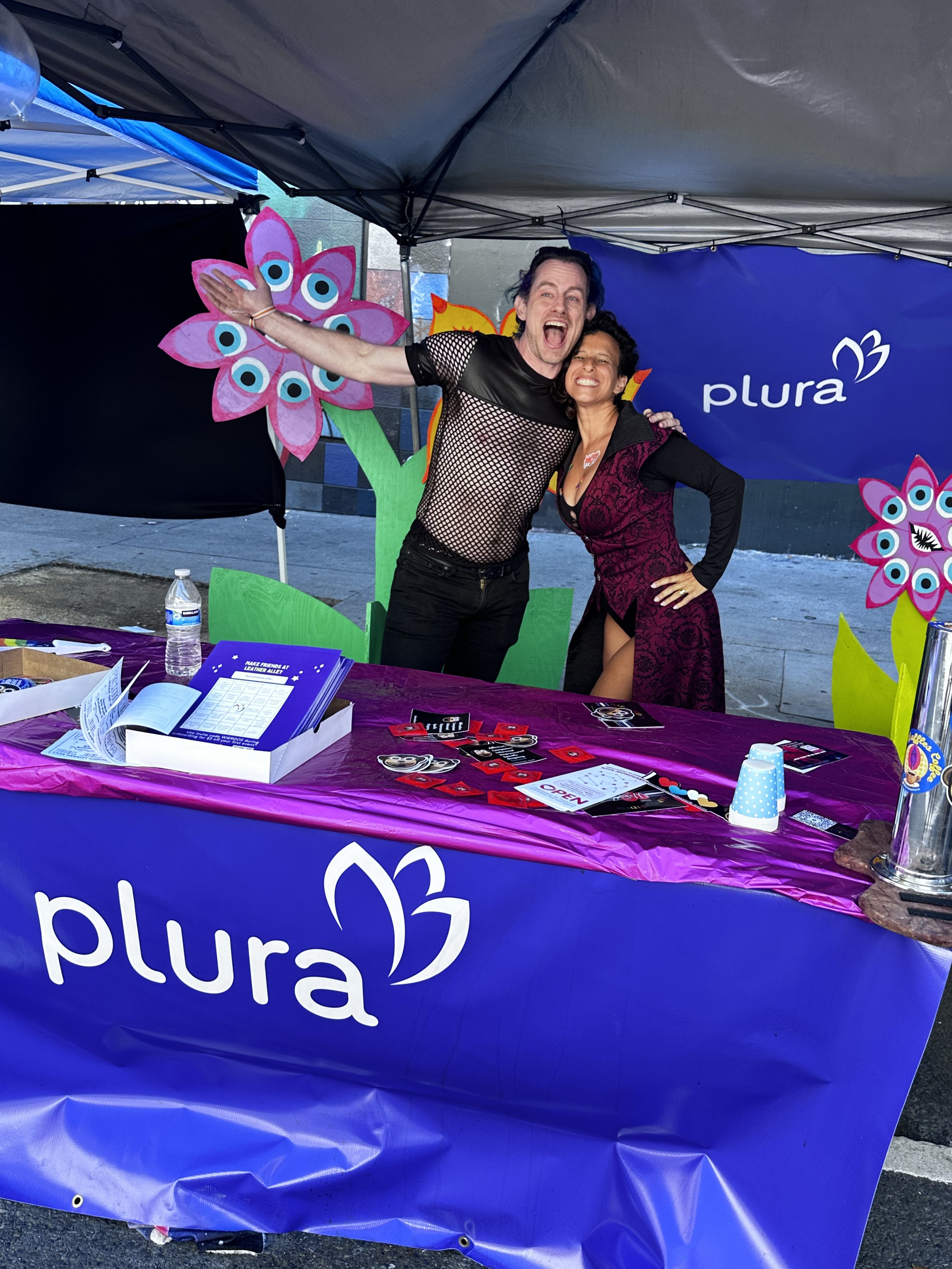 White Man and women standing behind a table with the Plura logo.