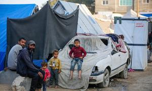 Una familia sentada frente a un refugio en Gaza.