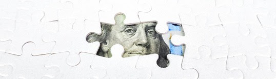 Ben Franklin, the face of the $100 bill, hidden behind puzzle pieces.