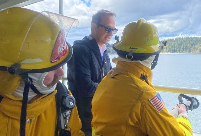 Ferry crewmembers help a student use firefighting gear