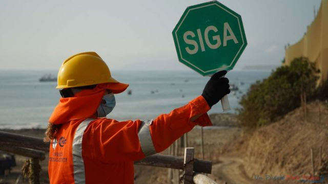 Operário segura placa em que se lê 'siga' no porto de Chancay