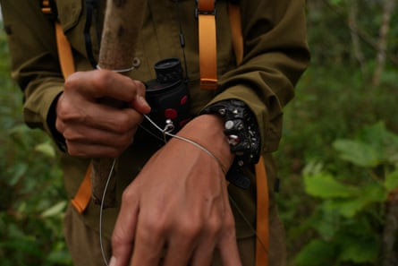 A woman in ranger’s uniform demonstrates using a snare wire around their wrist