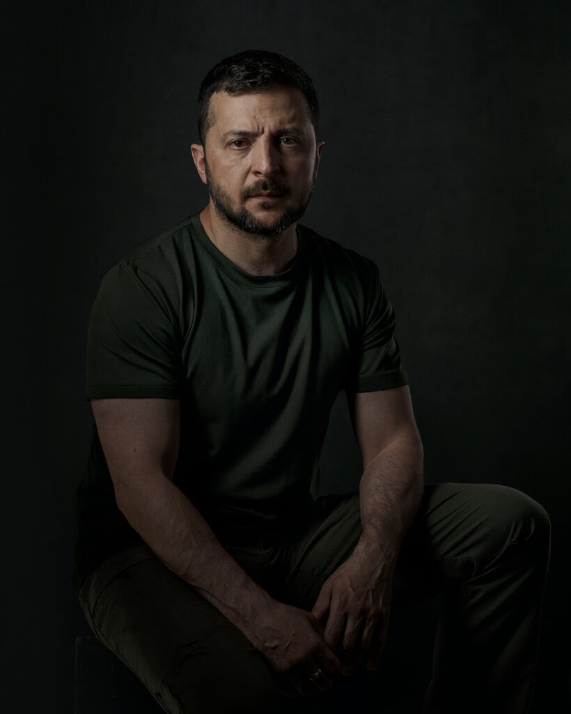 Volodymyr Zelensky in a green T-shirt against a dark background.