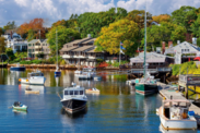 Ships docked in a marina during the fall. Trees with changing leave colors are in the background. Credit: Adobe Stock