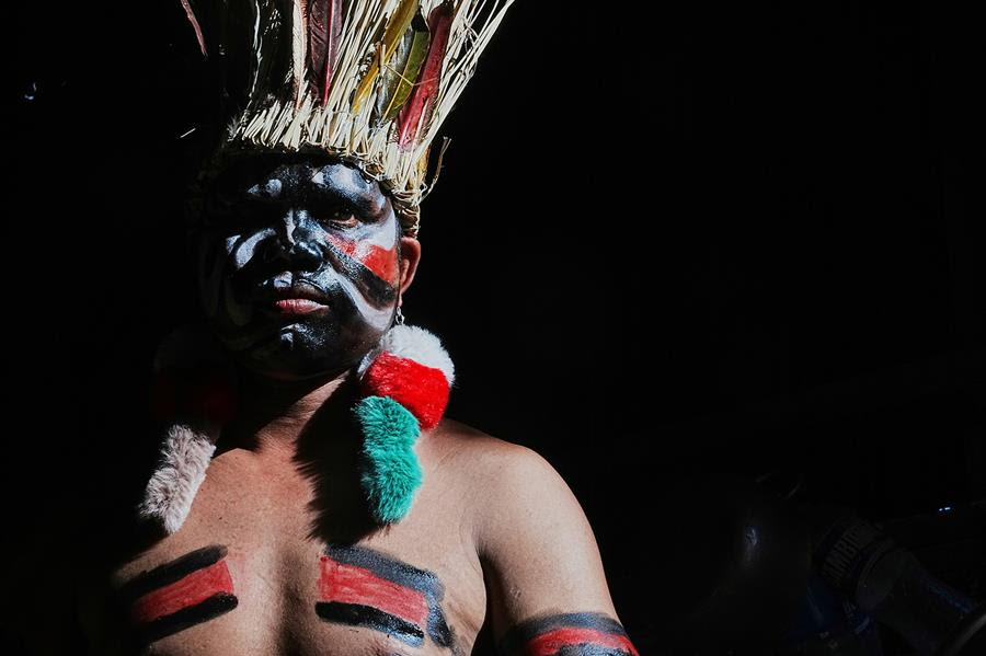 A man with a face painted stares straight forward.