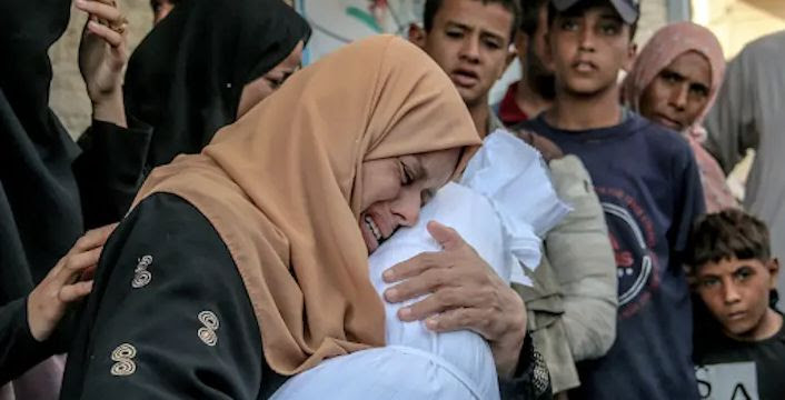 Des parents font leurs adieux à leur enfant tué lors d'une attaque israélienne sur le camp de réfugiés d'Al-Nuseirat, le 1er octobre 2024. Photo par Saeed Jaras