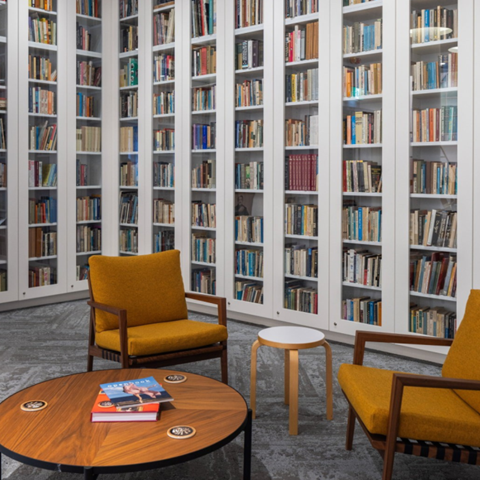A room with mustard coloured chairs and a coffee table. A white bookcase in the background.
