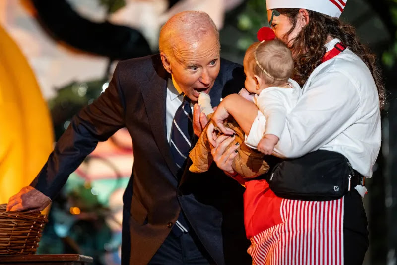 U.S. President Joe Biden playfully greets a baby as he and first lady Jill Biden welcome trick-or-treaters during a Halloween event at the White House in Washington, D.C., on Oct. 30.