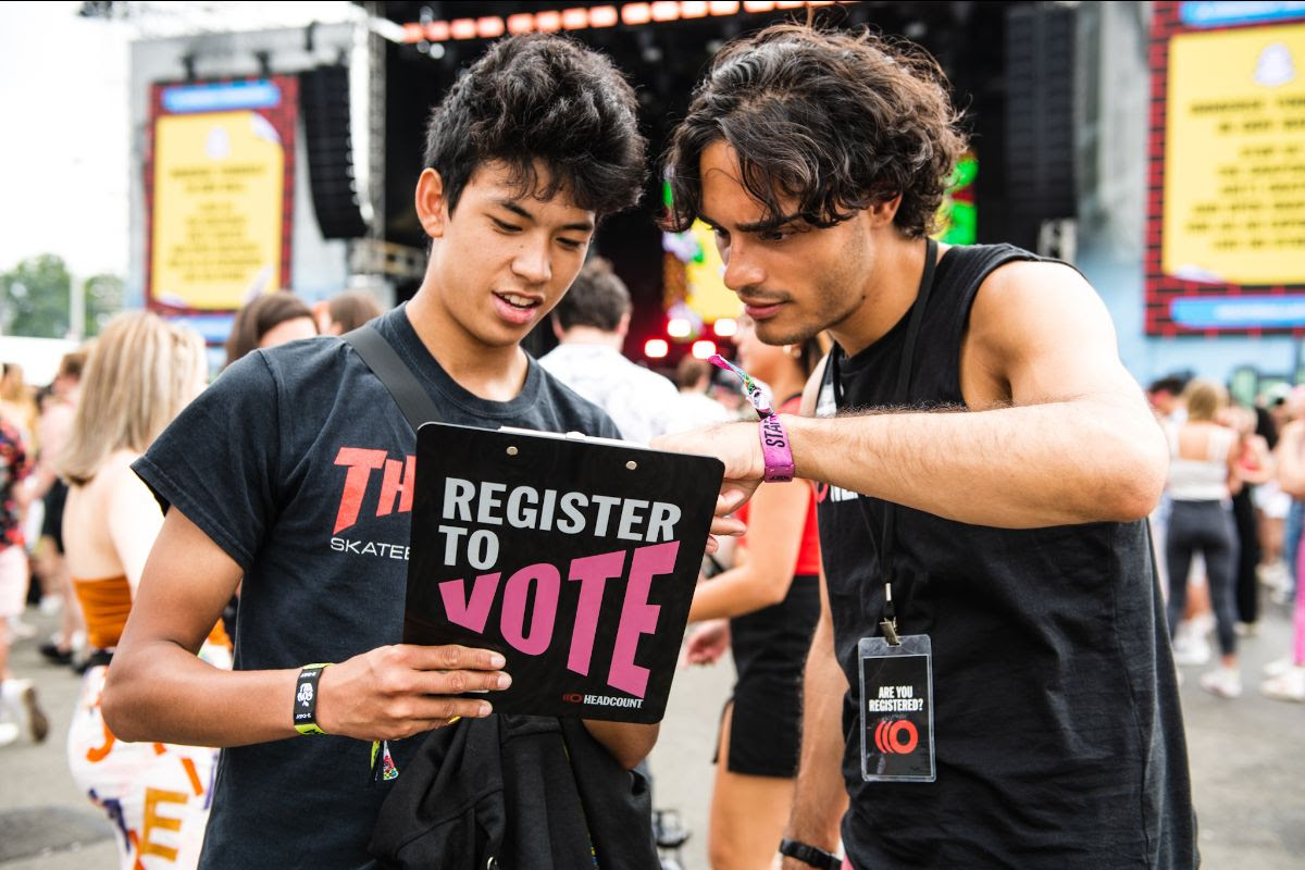 Two young men, one Asian and one Hispanic registering to vote at a HeadCount event