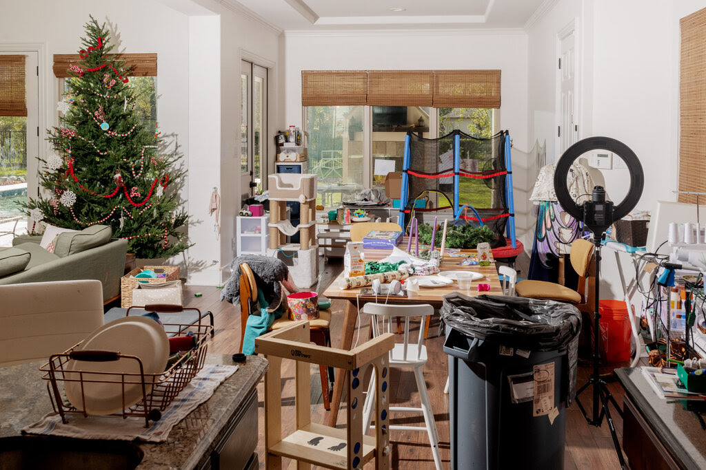 A cluttered room with a Christmas tree amid dozens of household items.