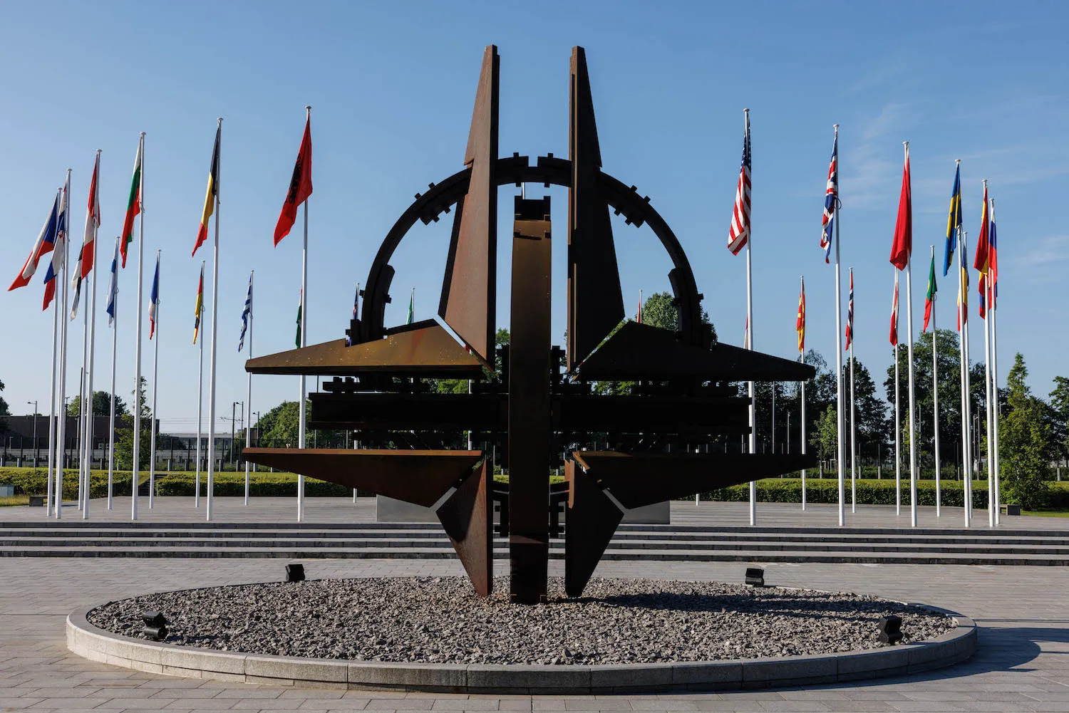 Flagpoles bearing national flags of NATO members adorn the entrance of NATO headquarters in Brussels on June 13.