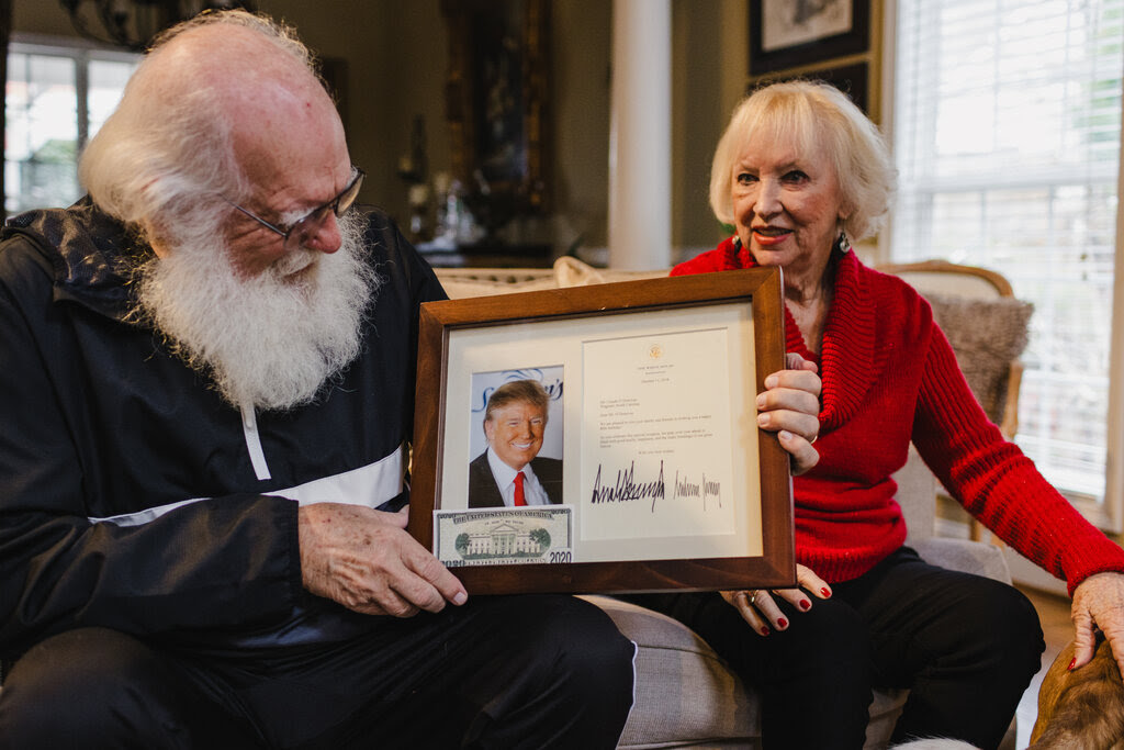 Claude O’Donovan holds up a signed photo of Donald Trump as he sits next to his wife, Sunny.