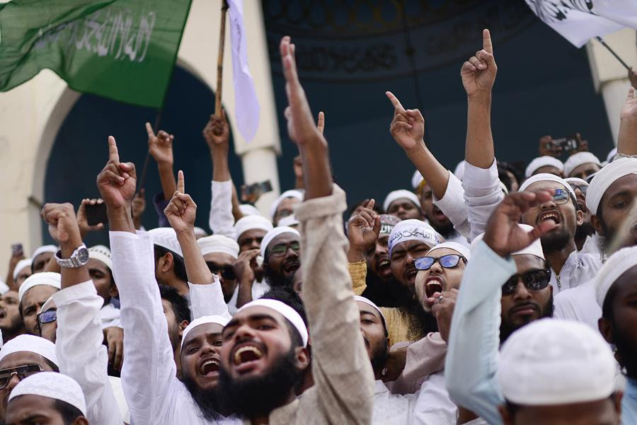 Hefazat-e-Islam supporters stage a protest after Friday prayers. Many of them have their hands raised.