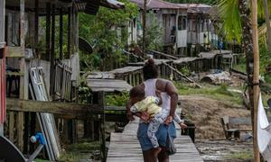 Una mujer afrodescendiente camina con su bebé en la comunidad Litoral del San Juan, Colombia.