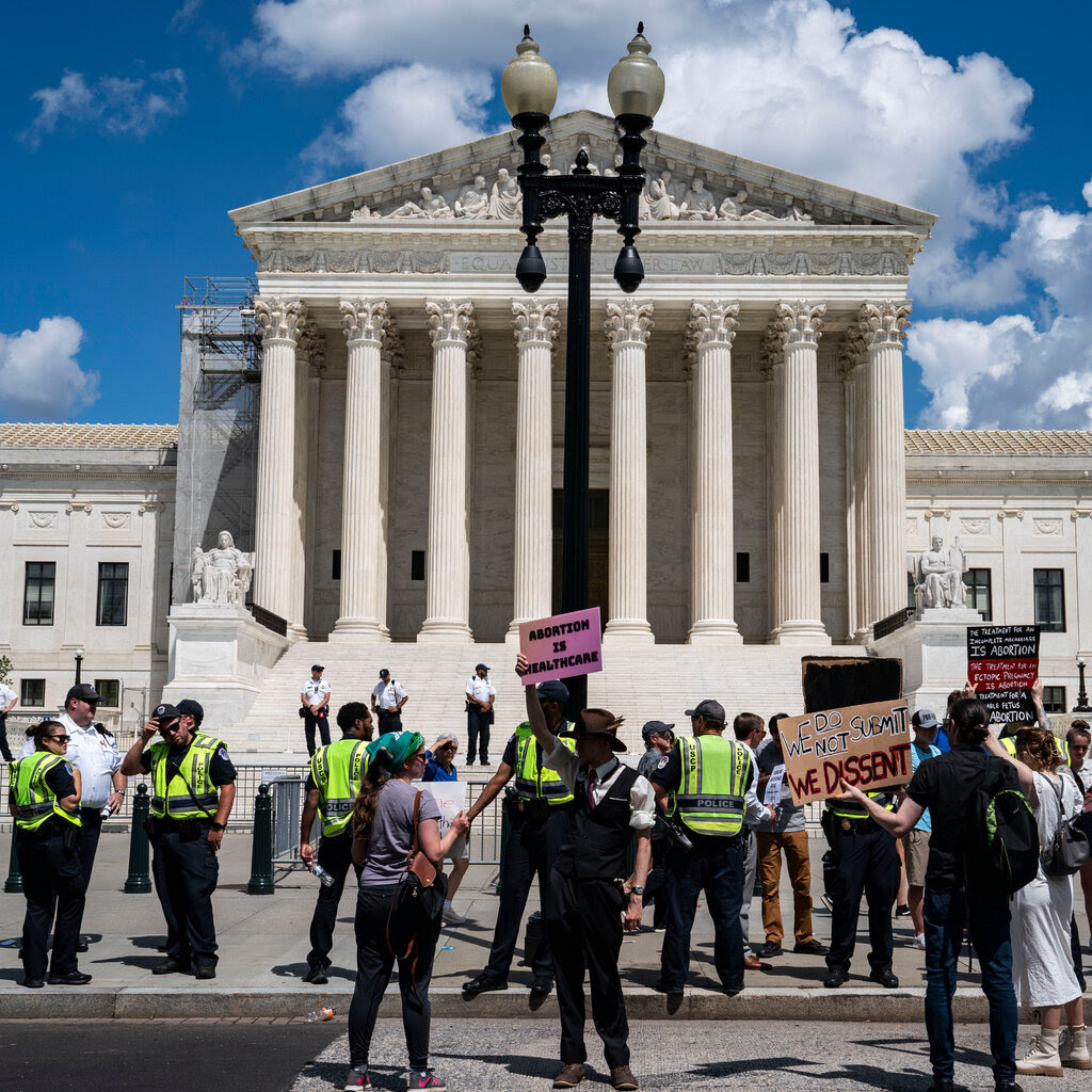 Protesters holding signs stand outside the Supreme Court. 