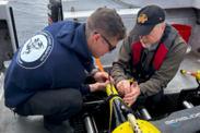 Two researchers on a boat prepare Seagliders for deployment on an overcast day on calm seas