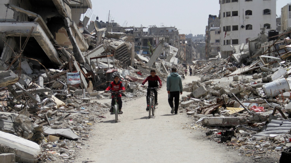 Palestinians ride bicycles past the ruins of houses and buildings destroyed during Israel’s military offensive, amid the ongoing conflict between Israel and Hamas in the northern Gaza Strip.