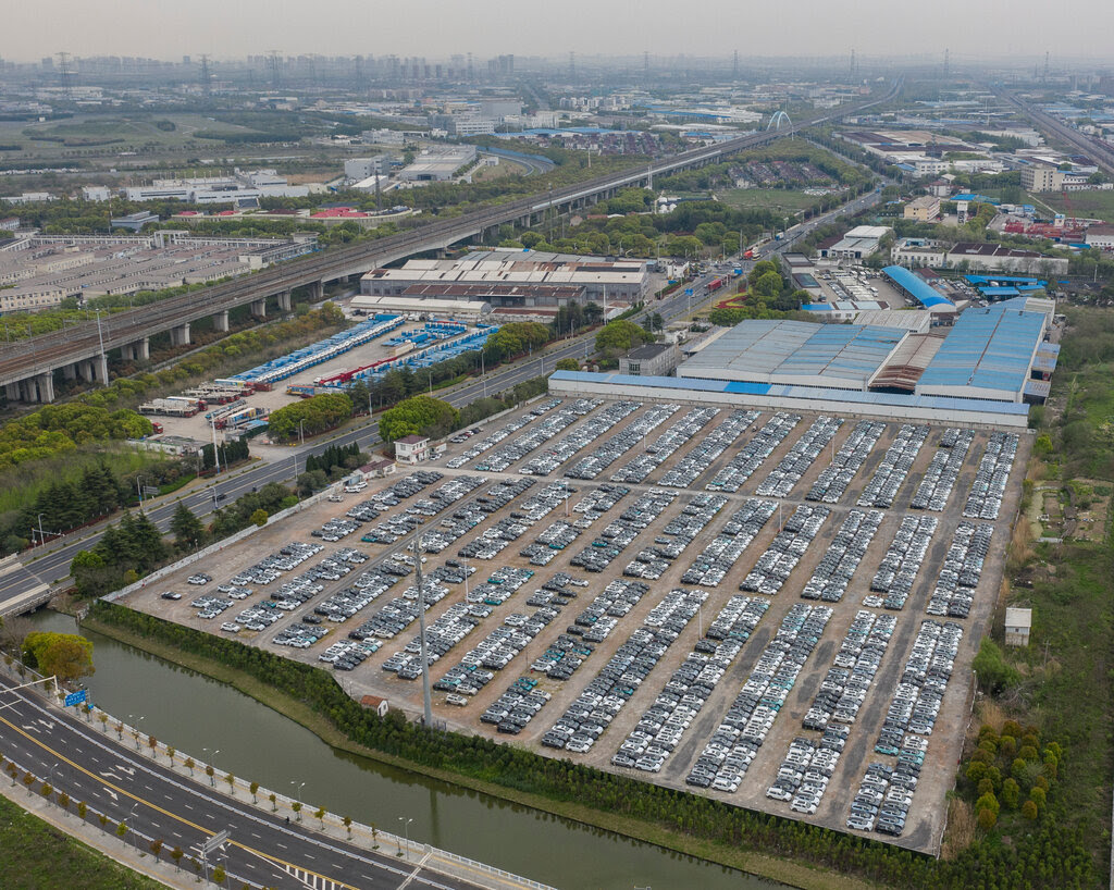 Aerial view of hundreds of newly assembled cars sit on a lot.