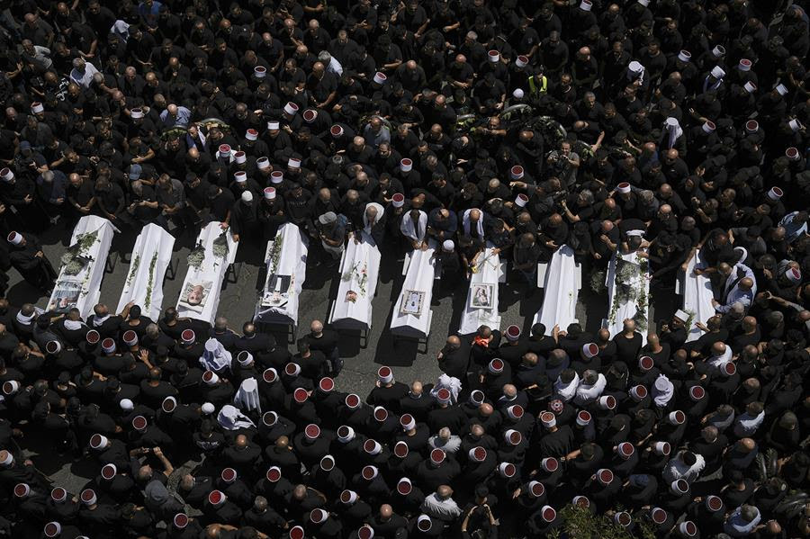 Members of the Druze community gather around the bodies of the children and teens killed in a rocket strike.