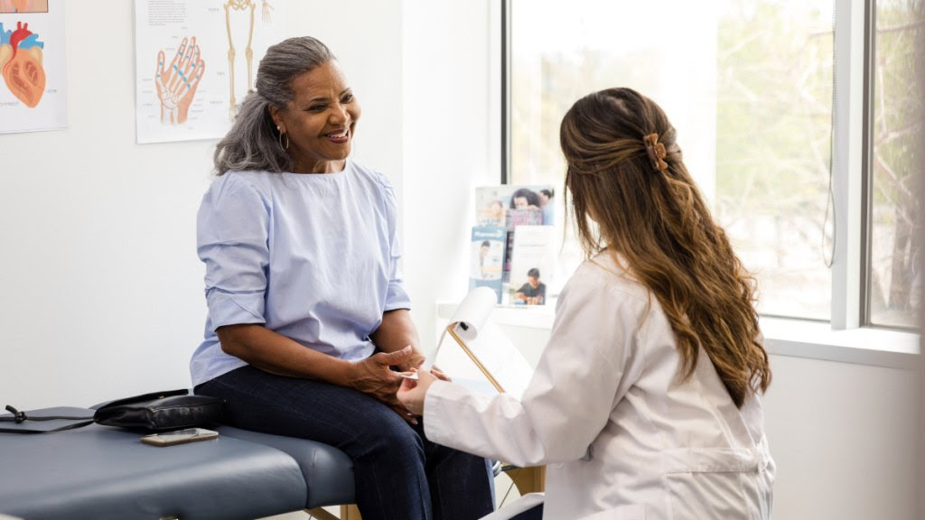 A woman on an exam table talking to her doctor in a doctor's office