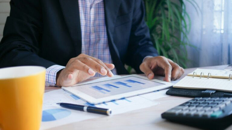 A business professional using a tablet at an office work desk.