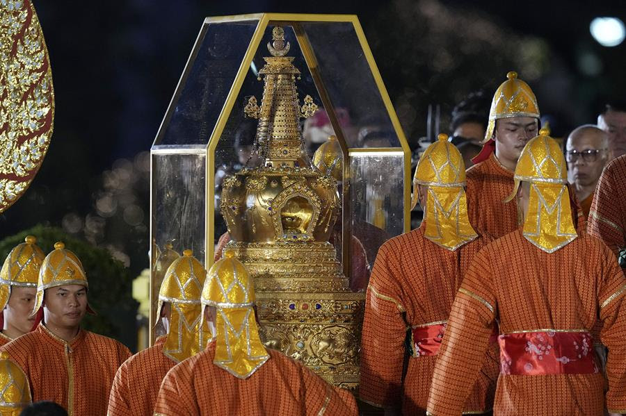 Officers dressed in orange and yellow carry Buddha's sacred tooth relics which are in a glass case.