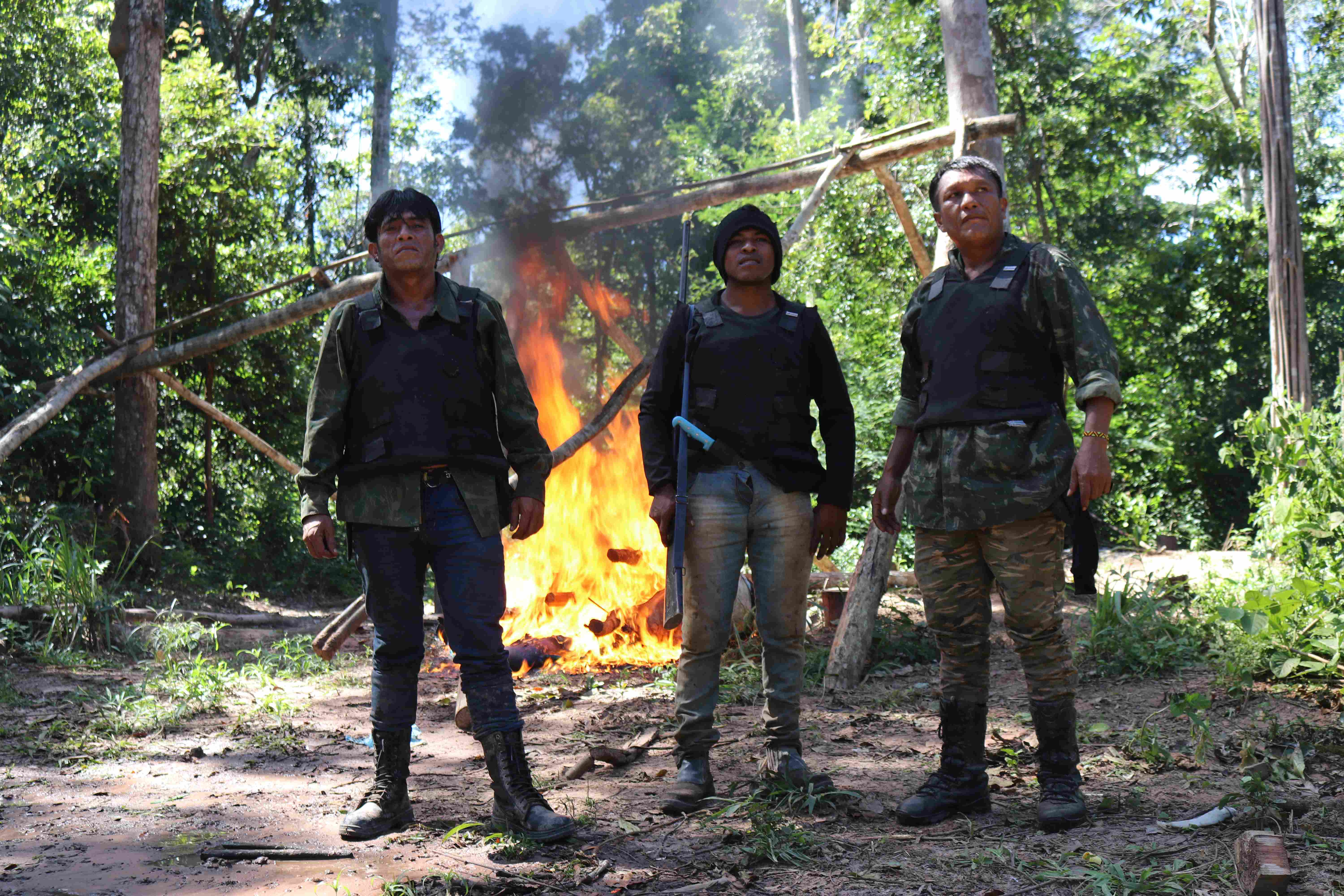 Guajajara Guardians stand before a fire in the forest.